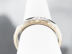 This vintage band is crafted entirely of 14k gold, with yellow gold framing the edge of the ring, and white gold creating a floral accented center. The center of this ring is slightly domed, giving it the ability to catch the light and accented by the waving, faceted edge. Metal: 14K Yellow and White Gold Width of Band: 6.5 mm Height off Finger: 2.1 mm Ring Size: 12.25 Marks: "14KT" Stamped on the inside band Yellow Gold Wedding Ring With Decorative Band, Yellow Gold Wedding Band With Decorative Detail, Timeless Yellow Gold Engraved Ring With Decorative Band, Fine Jewelry Wedding Rings With Milgrain Detail, Timeless Gold Engraved Ring With Decorative Band, Classic White Dome Ring For Wedding, Classic Gold Diamond Ring With Decorative Band, Classic White Gold Diamond Ring With Decorative Band, Luxury 14k Gold Engraved Ring With Decorative Band