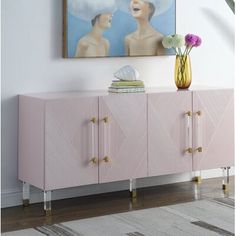 a pink sideboard with gold handles and two women in hats on the painting above it