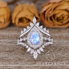 a ring with an oval shaped blue stone surrounded by white and clear diamonds on top of a wooden table