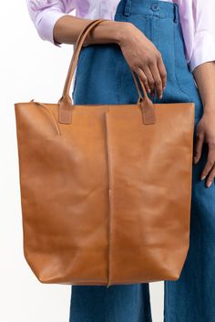 This large, durable leather tote is perfect for bringing along on trips to the farmers market, beach, or picnics. Crafted with high-quality 1.8mm vegetable-tanned Italian leather that is water-resistant and features a zippered shoulder bag design with a front-panel seam, key-hook, and spacious interior pocket. Natural Leather Bag Vegetable-tanned, Rectangular Vegetable-tanned Satchel For Travel, Travel Tote Bag With Vegetable-tanned Leather, Vegetable-tanned Leather Tote Satchel, Vegetable-tanned Leather Satchel Tote, Vegetable-tanned Leather Tote Shoulder Bag, Vegetable Tanned Leather Travel Tote Shoulder Bag, Vegetable Tanned Leather Tote Shoulder Bag For Travel, Travel Bucket Tote Bag