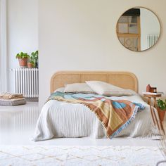 a bedroom with a bed, mirror and potted plants on the floor in front of it