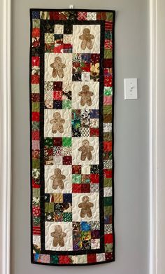 a teddy bear quilt hanging on the wall next to a white door with a light switch