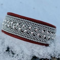 a close up of a bracelet in the snow