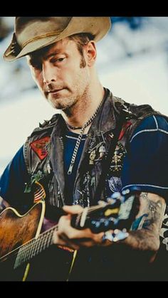 a man wearing a cowboy hat playing an acoustic guitar