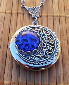 Blue Moon Victorian Style Round Silver Locket Necklace This spectacular vintage style locket is 32mm in diameter and features a blue vintage German cabochon circa 1950's The gem has a moon like appearance - textured reverse side makes it look like a cratered moon surface even though the gem itself is smooth. Very unusual and captivating. The gem is surrounded by an ornate and highly detailed crescent moon stamping which was oxidised to bring out the beautiful ornamental details. The locket is joined to the chain by an antiqued silver plated brass connector which is also very intricate. The stainless steel textured cable chain is 64cm long finished with a lobster clasp.  On the left side of the chain i added a cobalt blue Czech glass crystal bead and another tiny silver plated and oxidised Stainless Steel Texture, Victorian Filigree, Moon Surface, Silver Locket Necklace, Silver Locket, Sapphire Wedding, Silver Lockets, September Birthstone, Silver Filigree