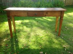 a wooden table sitting on top of a lush green field