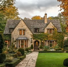 a stone house surrounded by lush green trees and bushes in front of it is an entry way to the home