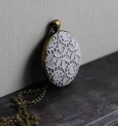 "This pendant is made with new white floral lace that has a vintage yet modern style, and is perfect for bridesmaid jewelry and shower gifts, as well as a unique everyday piece. The fabric is light gray cotton, and the pendant is made of dark bronze color alloy. The chain is shown at 30 inches, but you can choose a custom length for the perfect fit. Find similar neutral pieces in this section of my shop (scroll past the main heading to view): https://www.etsy.com/shop/TheWhirlwind?section_id=144 White Lace Necklace For Wedding, Vintage White Necklace For Weddings, Vintage White Necklaces For Wedding, Delicate White Necklace For Wedding Gift, Vintage White Wedding Jewelry, White Vintage Wedding Jewelry, White Lace Jewelry With Lace Trim, White Filigree Necklace Gift, Elegant Lace Trim Jewelry For Gift