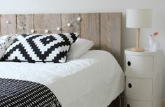 a bedroom with a white bed and black and white decor on the headboard, night stand and nightstand