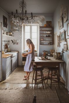 a woman standing in a kitchen next to a table