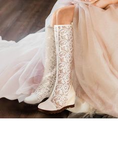 a woman wearing white boots sitting on top of a wooden floor next to a dress