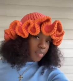 a woman wearing an orange knitted hat with large flowers on it's head