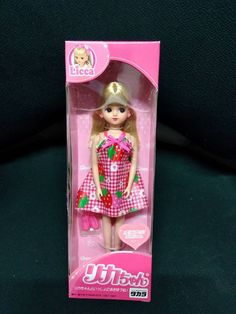 a barbie doll in a pink box on a black background