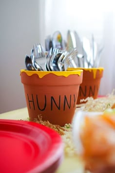 there are two pots with forks and spoons in them on the table next to each other