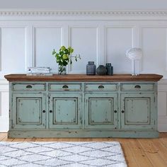 an old green cabinet in a white room with a rug on the floor next to it