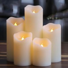 five lit candles sitting on top of a wooden table next to a black couch with chinese writing