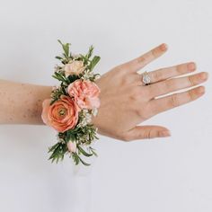 a person's hand with a ring on it and some flowers in the middle