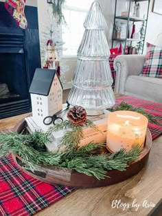 a christmas centerpiece with pine cones, candles and other decorations on a wooden tray