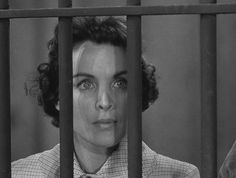 a woman in a shirt and tie behind bars