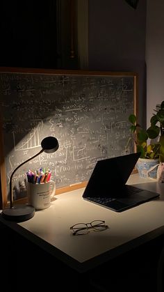 a laptop computer sitting on top of a desk next to a cup with pencils