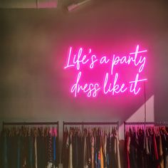 a neon sign that says life's a party dress like it on the wall