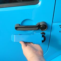 a hand is holding the door handle on a blue car