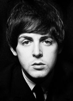 a black and white photo of a young man in a suit looking at the camera