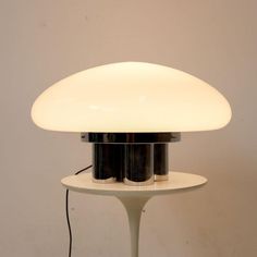 a white table lamp sitting on top of a white table next to a wall mounted light