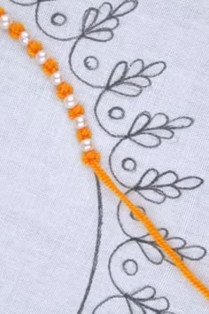 a close up of a piece of cloth with beads on it and an orange thread