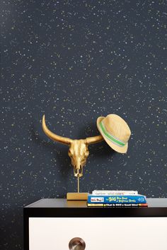 a gold bull's head with a hat on top of it next to a white dresser