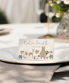 a place card is placed on a plate with flowers and deers in the background