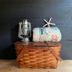 a basket sitting on top of a wooden table next to a starfish and lantern