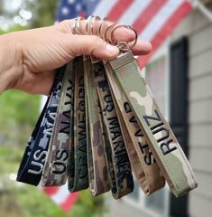 a person holding several key chains in front of a house with an american flag on it