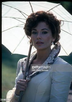 a woman holding an umbrella in her hand and posing for the camera, outdoors stock photo