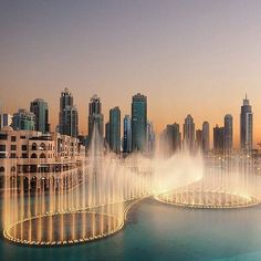 an aerial view of a city with fountains in the foreground and skyscrapers in the background