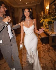 a woman in a white dress and a man in a gray suit are dancing together