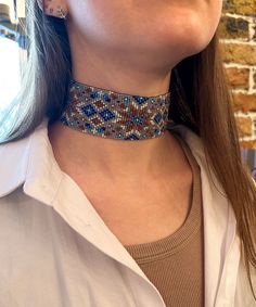 a close up of a woman wearing a blue and brown beaded choker necklace