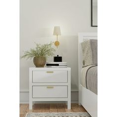 a white nightstand with a plant on it next to a night stand and a bed