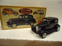 an old model car is next to a boxed version of the 1932 ford victoria toy