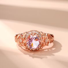 This exquisite piece showcases a captivating combination of elegance and femininity. Crafted in sterling silver, this beautiful ring showcases a sparkling round-cut morganite stone radiating a soft and romantic glow and flower detailing along the ring's shank lending heirloom appeal to this elegant design. Delicate and romantic, this ring is the perfect choice for her.Carat Weight: 1.28 ctStone Size: 7 mmStone Type: Jeulia® StoneNumber of Stones: 1 Stone Shape: RoundStone Color: Fancy PinkCarat Weight: 0.394 ctStone Size: 1,1.3,1.4,1.6,1.8 mmStone Type: Jeulia® StoneNumber of Stones: 16 Stone Shape: RoundStone Color: Diamond WhiteWeight: 4.5 gWidth: 1.1 mmHeight: 7.4 mmThickness: 2.8 mmMaterial: 925 SilverPlating Color: Rose Gold Elegant Pink Gemstone Ring, Elegant Pink Gold Rings With Accent Stones, Rose Gold Flower Ring With Center Stone For Promise, Luxury Rose Gold Topaz Ring With Prong Setting, Elegant Solitaire Pink Gold Jewelry, Formal Rose Gold Morganite Diamond Ring, Round Pink Gold Diamond Ring, Pink Gold Round Diamond Ring, Elegant Pink Gold Jewelry With Center Stone