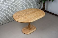 a wooden table sitting in front of a brick wall next to a potted plant