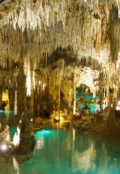 the inside of a cave with blue water and icicles hanging from it's ceiling