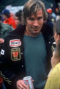 a man with long hair wearing a jacket and holding a can