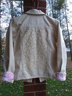 This short, khaki jacket is made by Denim & Co. It is embellished with a hand made, crocheted applique; hand-stitched on the back.  The tag says extra small, but Denim & Co runs big, so it fits like a small. Pit to Pit measurement is 19.5 inches, so bust measurement would be 39. It is 21 inches long. 100% lightweight cotton denim. Pink trim at the inside back neck and cuffs. Beautiful, professionally done, quality seams. Perfect for a young girl. Cotton Long Sleeve Outerwear With Lace Trim, Long Sleeve Cotton Outerwear With Lace Trim, Khaki Denim Jacket With Button Closure, Beige Long Sleeve Denim Jacket, Beige Denim Jacket With Pockets, Fitted Crochet Cotton Outerwear, Khaki Cotton Button-up Denim Jacket, Beige Cotton Button-up Denim Jacket, Off White Jacket