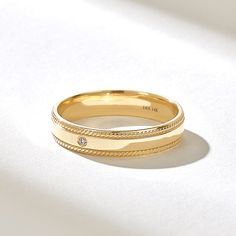 two yellow gold wedding bands with diamonds on white tablecloth, close - up view