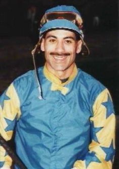 a man wearing a jockey's uniform and holding a baseball bat in his hand