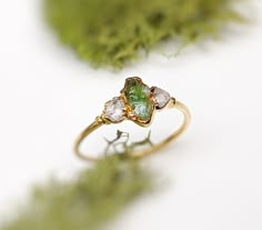 three stone ring sitting on top of green moss