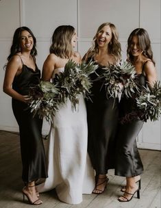 three beautiful women standing next to each other holding bouquets in their hands and smiling at the camera