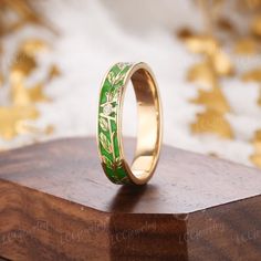 a gold ring with green leaves painted on it