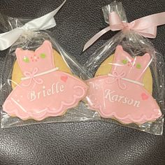 two decorated cookies in plastic wrappers with bows on the top one is pink and the other is yellow